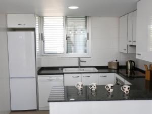 a kitchen with white cabinets and a black counter top at Holiday Home Xaloc in L'Ampolla