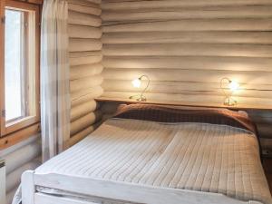 Bett in einem hölzernen Zimmer mit zwei Leuchten in der Unterkunft Holiday Home Kalliokoivu by Interhome in Torvoila