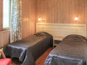 two beds in a room with wooden walls and wooden floors at Holiday Home Kalliokoivu by Interhome in Torvoila