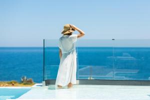 Una mujer con un vestido blanco mirando hacia el océano en Wave Villa, Seaside Living & Your Own Beach Spot, By ThinkVilla, en Panormos Rethymno 37 fotos más