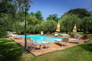 una piscina con sillas, mesas y sombrillas en Villa Casa Tonio, en Valgiano