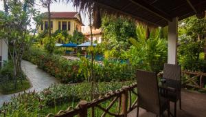 a view of a garden with two chairs and a house at La Rivière d' Angkor Resort in Siem Reap