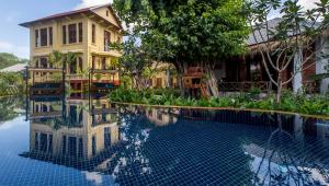 a house and a swimming pool in front of a house at La Rivière d' Angkor Resort in Siem Reap