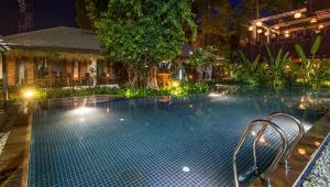 a swimming pool at night with a tree and lights at La Rivière d' Angkor Resort in Siem Reap
