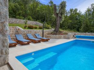 a pool with lounge chairs next to a stone wall at Holiday Home Villa Matija by Interhome in Drivenik