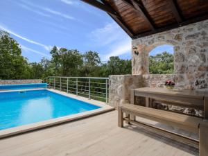 an outdoor deck with a swimming pool and a bench at Holiday Home Villa Matija by Interhome in Drivenik