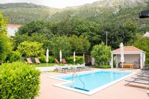 a villa with a swimming pool and mountains in the background at Apartments Tabain in Mlini