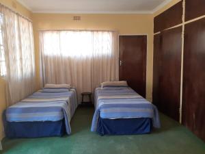 two beds in a room with a window at Aruka - Formerly Grace Lodge in Bela-Bela