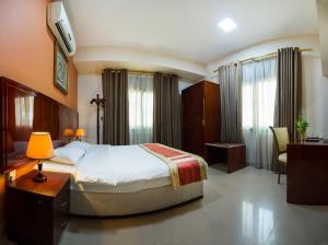 a bedroom with a bed and a desk and a tv at Safeer Plaza Hotel in Muscat