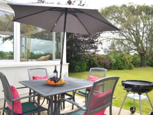 GaerwenにあるHoliday Home Caernarfon View Cottage by Interhomeの黒いテーブル(椅子、傘付)