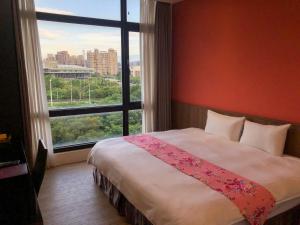 a bedroom with a large bed with a large window at Sendale Zhubei Business Hotel in Zhubei