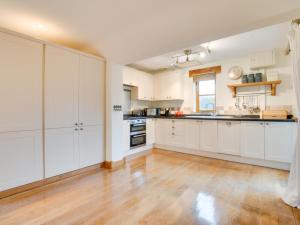 una cucina con armadietti bianchi e pavimenti in legno massello di Holiday Home Maes Remyr by Interhome a Dolgellau