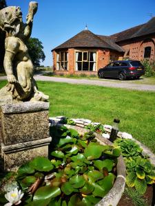 posąg siedzący obok stawu lilii wodnych w obiekcie The Round House at Boningale Manor w mieście Wolverhampton