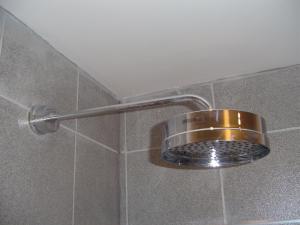 a shower with a metal shower head in a bathroom at Aaron Glen Apartments in Edinburgh