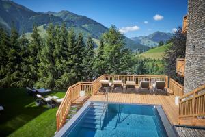 um deque com piscina e montanhas ao fundo em AlpenParks Hotel & Apartment Sonnleiten em Saalbach Hinterglemm