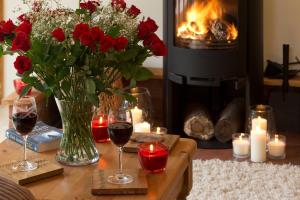 a table with red roses and candles and a fireplace at Owl's Hoot in Thorndon