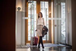 a woman walking through a glass door with a suitcase at Jump INN Hotel Belgrade in Belgrade +67 photos