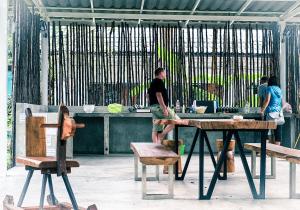 a man standing in front of a table with benches at Green tree house 度假屋 in Ko Chang