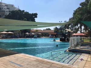 a large swimming pool with people in the water at Kfar Maccabiah Business & Sport Hotel in Ramat Gan