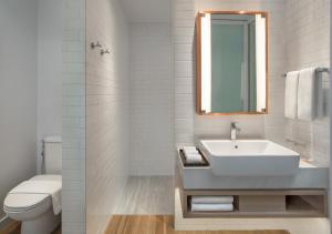 a bathroom with a sink and a toilet and a mirror at Brittany Hotel BGC in Manila