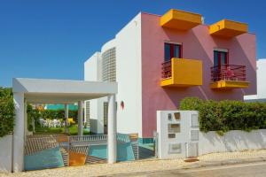 - un bâtiment rose et blanc avec des chaises et une terrasse dans l'établissement Vila Marina, à Albufeira