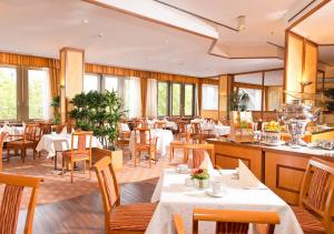 Hotel Steglitz International في برلين: مطعم بطاولات بيضاء وكراسي ونوافذ