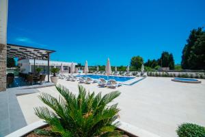 una piscina con sedie a sdraio e ombrelloni di Hotel Ambiente Ulcinj a Ulcinj