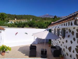 ein weißer Regenschirm und Stühle auf einer Terrasse in der Unterkunft Holiday Home LaCerca in Icod de los Vinos