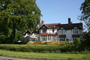una grande casa bianca e rossa situata sul ciglio di una strada di The Round House at Boningale Manor a Wolverhampton