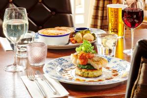 a table with a plate of food and wine glasses at The Jug And Bottle in Heswall