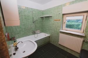 een groene badkamer met een wastafel en een raam bij Apartmaji Retro in Spodnje Gorje