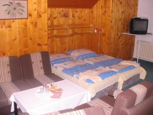 a bed in a room with a table and chairs at Penzion Pstruh in Stožec