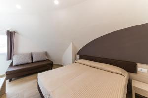 a small bedroom with a bed and a couch at Torre Cintola Greenblu Sea Emotions in Monopoli
