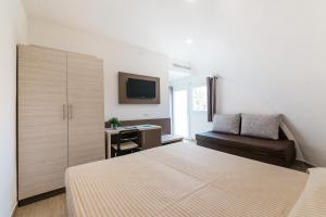 a bedroom with a bed and a couch and a television at Torre Cintola Greenblu Sea Emotions in Monopoli