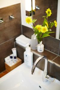 a bathroom sink with a vase with yellow flowers in it at Steinbergs Wildewiese NaturHotel in Wildewiese