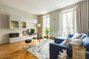 a living room with a blue couch and a tv at Veeve - Jazzy Blues by Châtelet in Paris