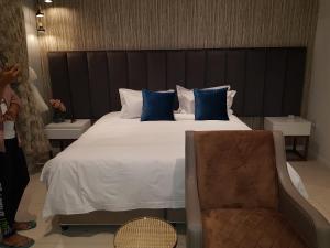 1 dormitorio con 1 cama grande con almohadas azules y silla en Green Avenue Apartments en Gaborone