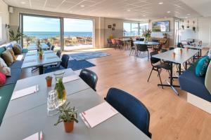 um restaurante com mesas e cadeiras e vista para o oceano em Stayokay Hostel Terschelling em West-Terschelling