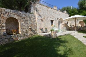 a stone building with an umbrella and a grass yard at La Corticella Bed & Breakfast in Martina Franca