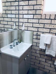 a bathroom with a white sink and a brick wall at Alfa motel in Gilgandra