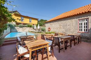 een patio met houten tafels en stoelen en een zwembad bij Casa do Eido - sustainable living & nature experiences Gerês in Geres