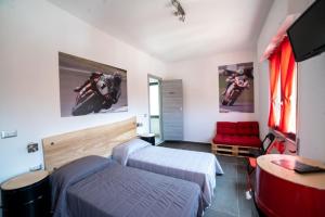 1 Schlafzimmer mit 2 Betten, einem TV und einem Sofa in der Unterkunft Italian Piston House Sport Moto Rent in Millesimo