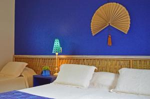 a bedroom with a blue wall with a fan and a bed at Pousada Mais Bella in Ilhabela +19 photos