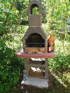 a stone oven sitting in the grass with two bottles at Summer bungalo trailer in Jūrmala