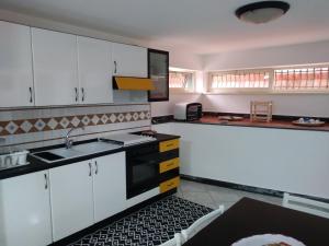 una cucina con armadi bianchi e un forno a piano cottura nero di Fata dell'Etna a Pedara