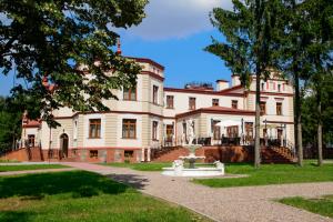 Une grande maison blanche avec une fontaine en face de celle-ci dans l'établissement Pałac Myślęta, à Uzdowo