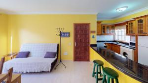 a bedroom with a bed and a kitchen with yellow walls at Mi Posadita - Salto Ángel in Playa de San Juan