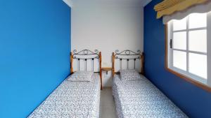 two beds in a room with blue walls and a window at Mi Posadita - Salto Ángel in Playa de San Juan