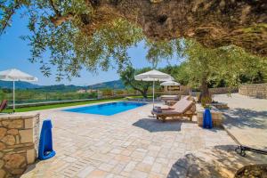 een zwembad met 2 ligstoelen en parasols bij Villa Vakis in Lithakia