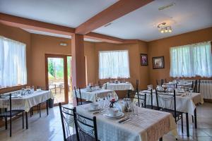 a restaurant with tables and chairs with white tablecloths at Guest House Slunchev Cviat in Tsigov Chark